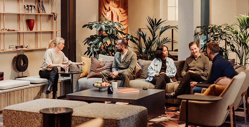 fem medarbejder der holder et uformelt møde i en sofa