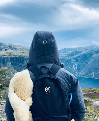 Person med Coor rygsæk ser ud over en fjordsø omgivet af bjerge