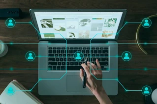 Person der arbejder på en bærbar computer med digitale netværksforbindelser og interaktionsikoner, moderne hjemmekontormiljø.