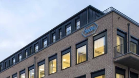 Moderne kontorbygning med 'Roche' logo, belyste vinduer i tusmørke.
