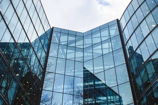 Moderne glasfacade på kontorbygning med spejling af himmel og bygning i København, Danmark.