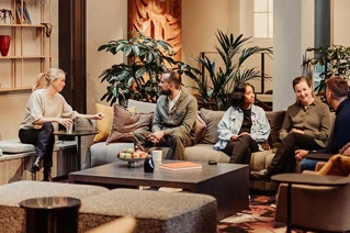 gruppe sidder i sofaer, samlet rundt om et bord
