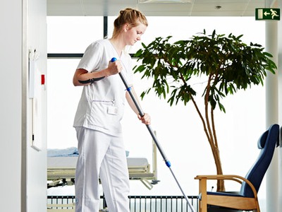 En medarbejder, der renser hospitalets gulv med en moppe | Coor