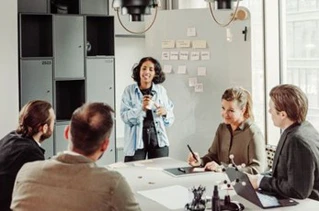 Kvinde fremlægger under møde i moderne kontorfaciliteter