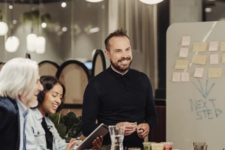 Levende diskussion på arbejdspladsen med glade kolleger og brainstorming-session ved whiteboard med post-its.