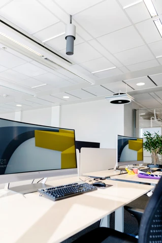 Moderne kontorlandskab med rene linjer og to computerskærme på et træskrivebord, designet til ergonomisk arbejdsplads i Danmark.