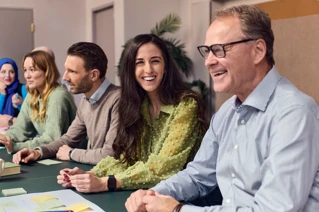 Diverse gruppe af smilende forretningsfolk i mødelokale, teamwork og samarbejde.